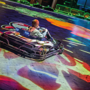Un joueur BattleVirus dans son kart avec des missiles qui partent en direction du gros virus vert